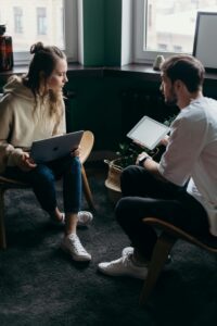 A couple having a thoughtful discussion with digital devices in a modern setting, reflecting collaboration and communication highlighting the importance of addressing stress in relationships collaboratively.